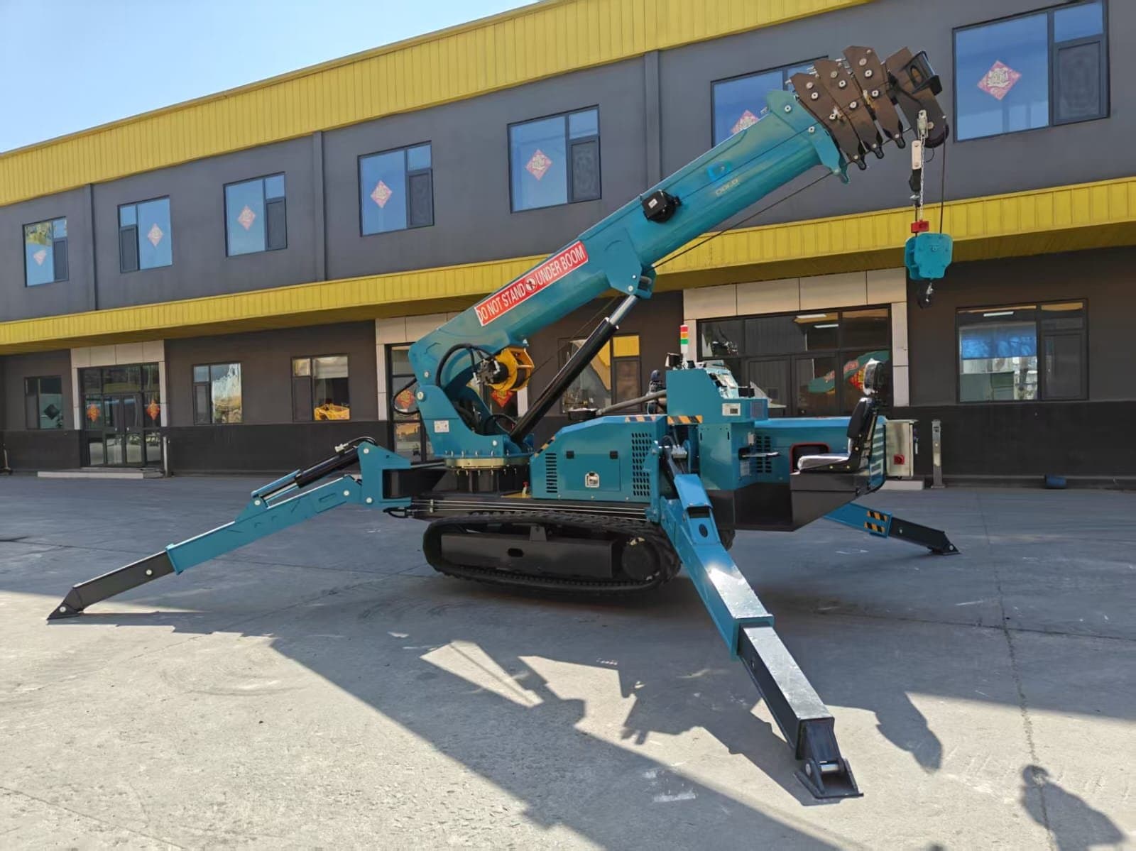 A spider crane with its four outrigger legs spread and the telescopic boom raised