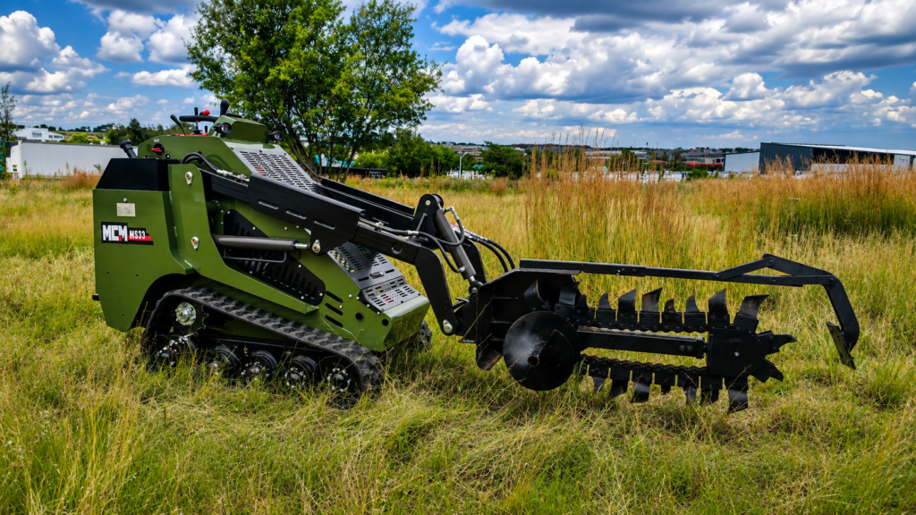 MCM MS33 mini track skidsteer fitted with a trencher attachment working in a grassy field