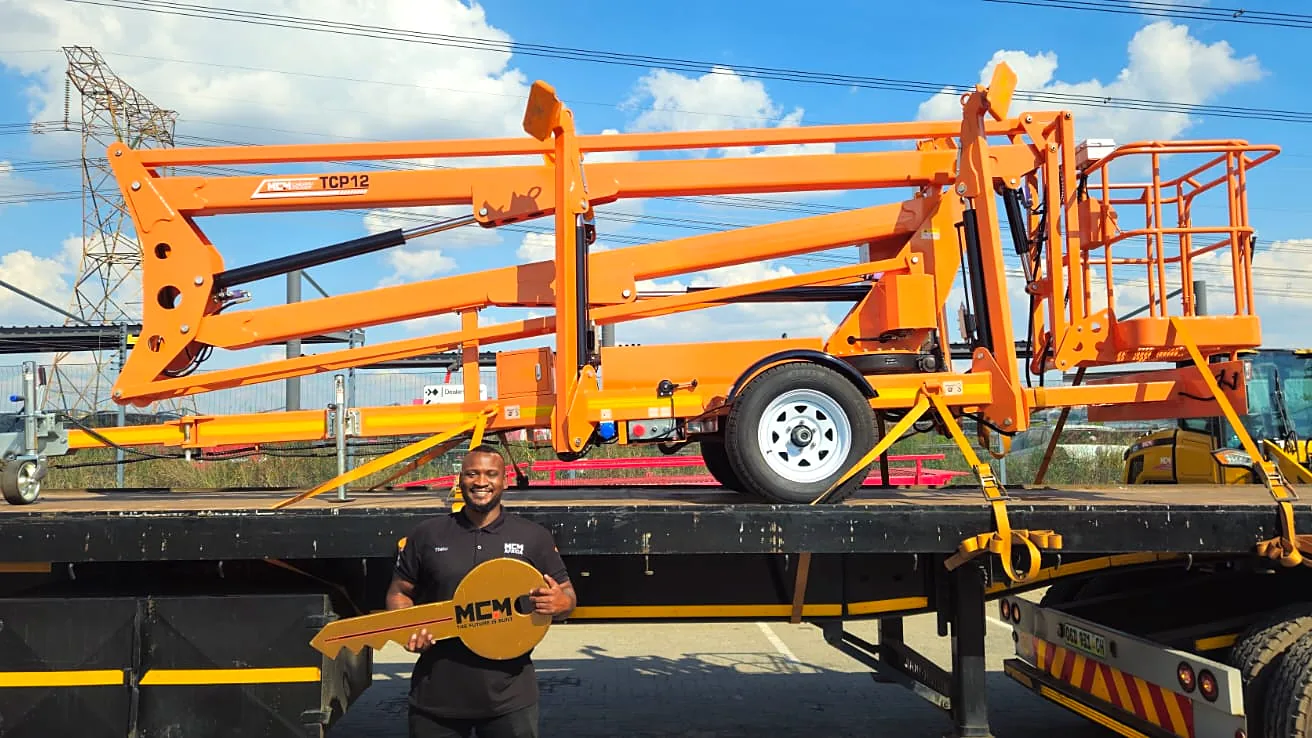New MCM towable cherry picker on a delivery truck with its new owner holding the keys