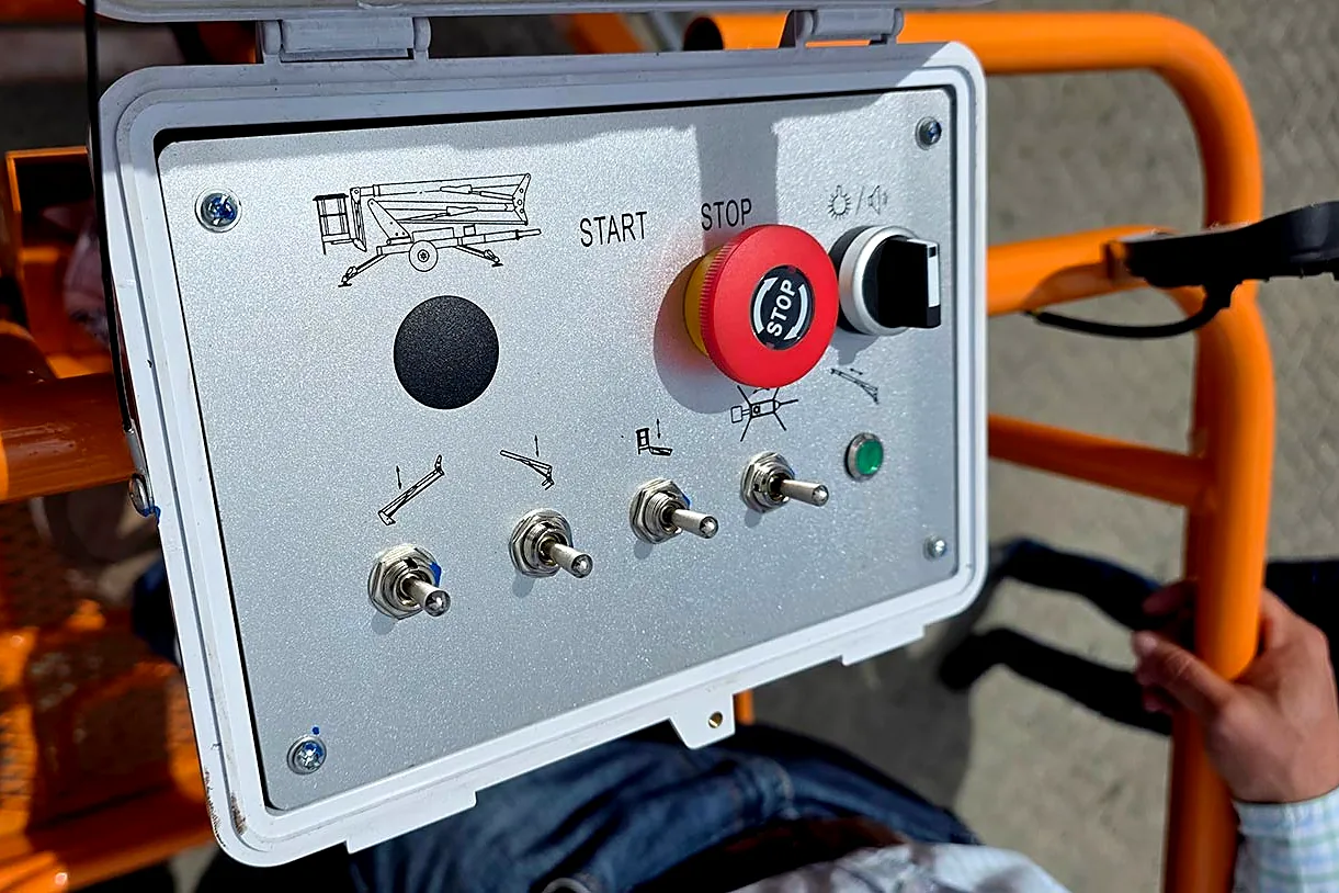 Close-up of the waterproof control panel and red emergency stop button on an MCM towable cherry picker