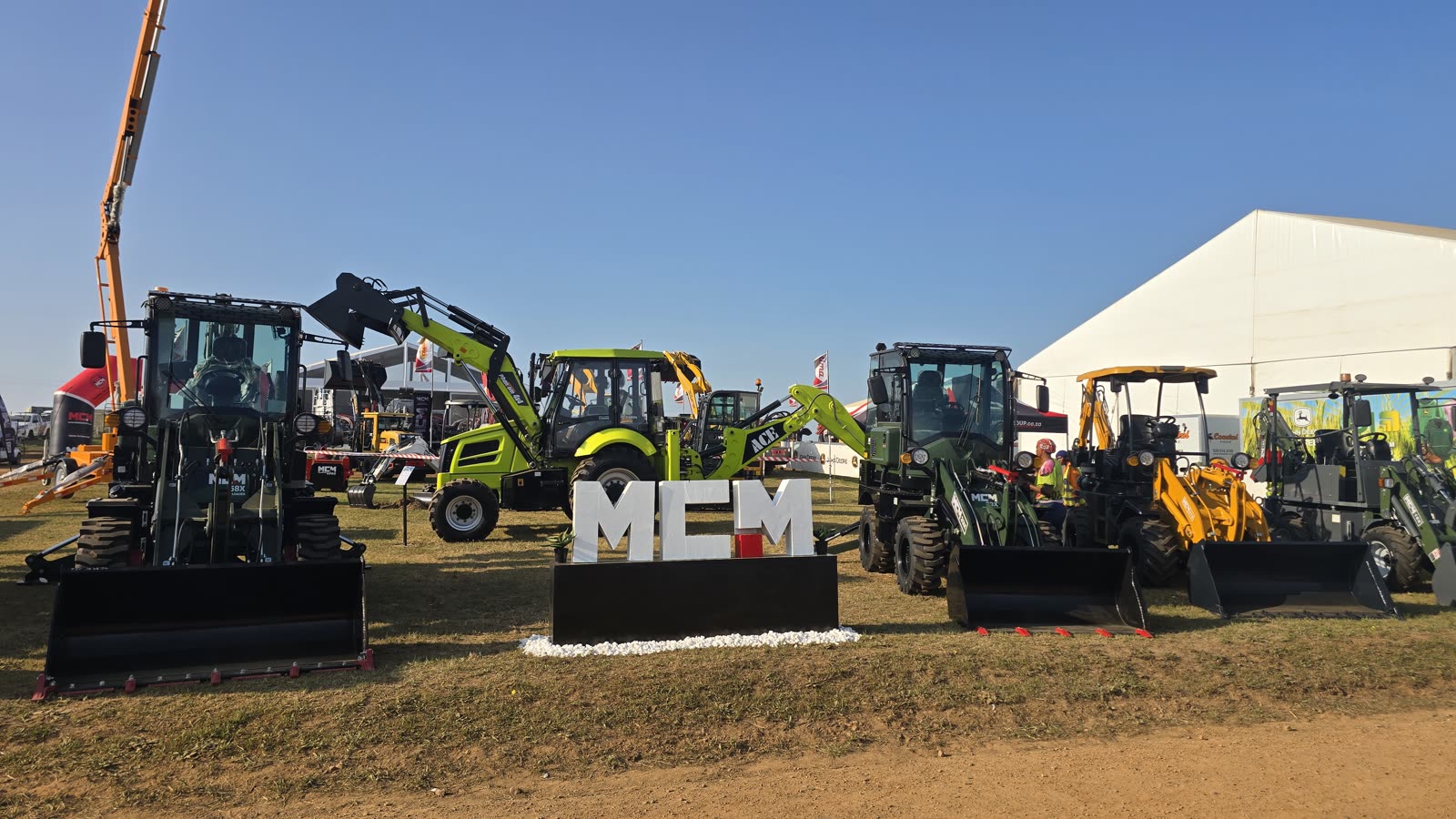 The MCM stand at NAMPO Cape 2026 in Bredasdorp with the 58X TLB, ACE Phantom backhoe loader and 33X TLB behind the MCM letters
